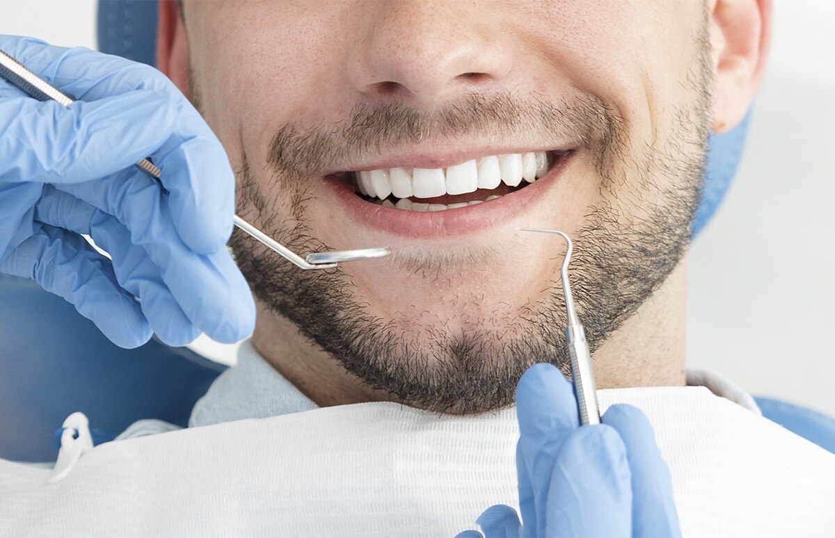 Procedimiento dental con instrumental clínico aplicado sobre la dentadura, con guantes y herramientas visibles en primer plano